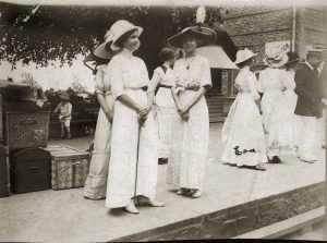 Eleganta damer i väntan på tåget när 1900 var ungt. Byggnaden bakom damerna var kiosken. På den ena kjolen står Eva och den andra Signe. OBS! Resekofferterna. Stationsbyggnaden är ombyggd - klar 1899.