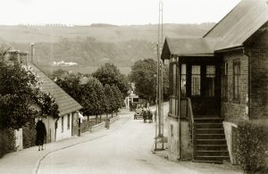 Lyckebacken (Köpmansgatan) Huset till vänster ägdes av åkaren Arvid Johansson. Därefter Gröna Torg och infarten till Agardhsgatan. Mitt i bilden Skåne-Hallands Järn- och Cykelaffär. Där syns även Brandquists bensinpump - CALTEX. Troligtvis är bilden tagen i början av 1930-talet.